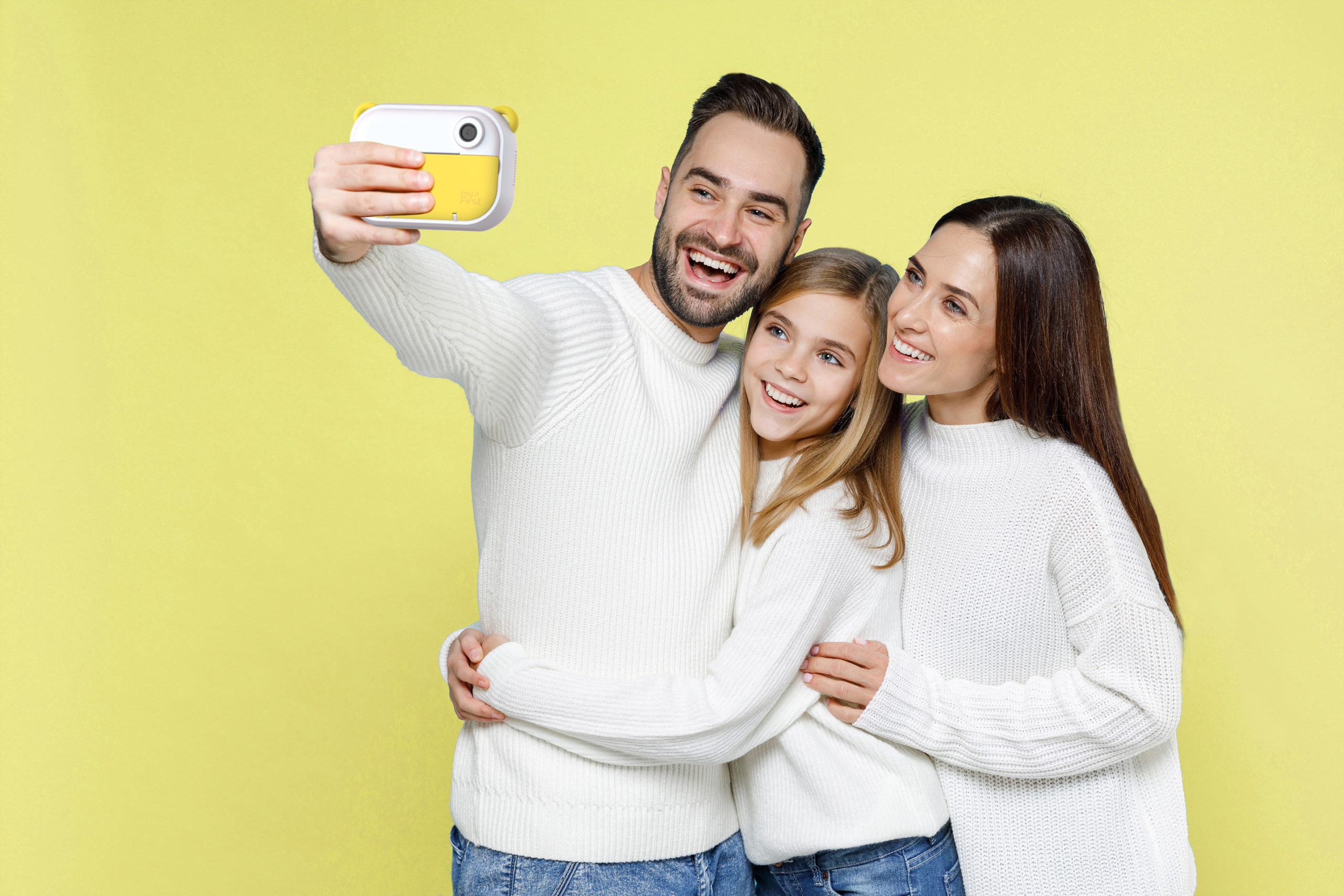 Happy young parents mom dad with child kid daughter teen girl in white sweaters doing selfie shot on mobile phone hugging isolated on blue background studio. Family day parenthood childhood concept