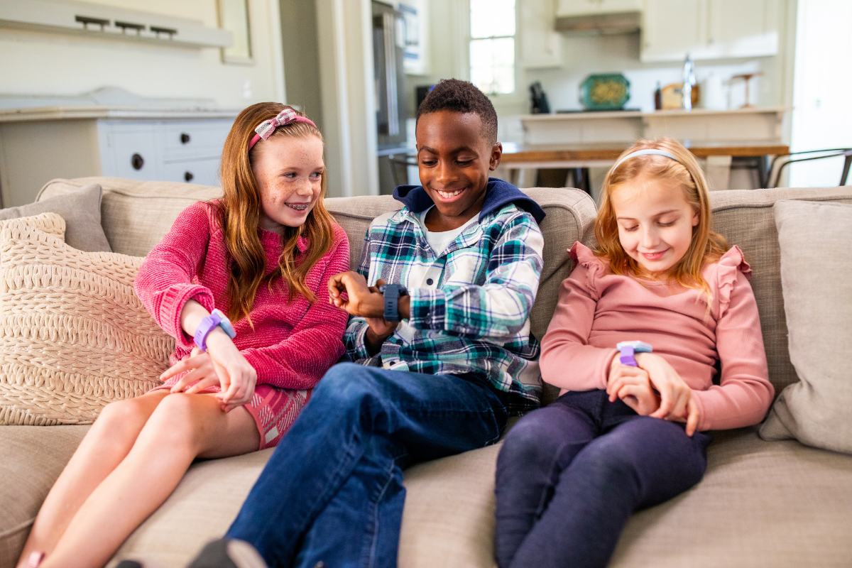 Three kids sitting on a couch enjoying their Fone S4 kids gps smartwatches from myFirst