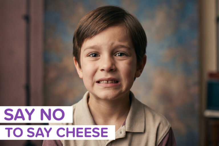 A kit struggling to smile naturally for a photo, with the label "say no to say cheese"